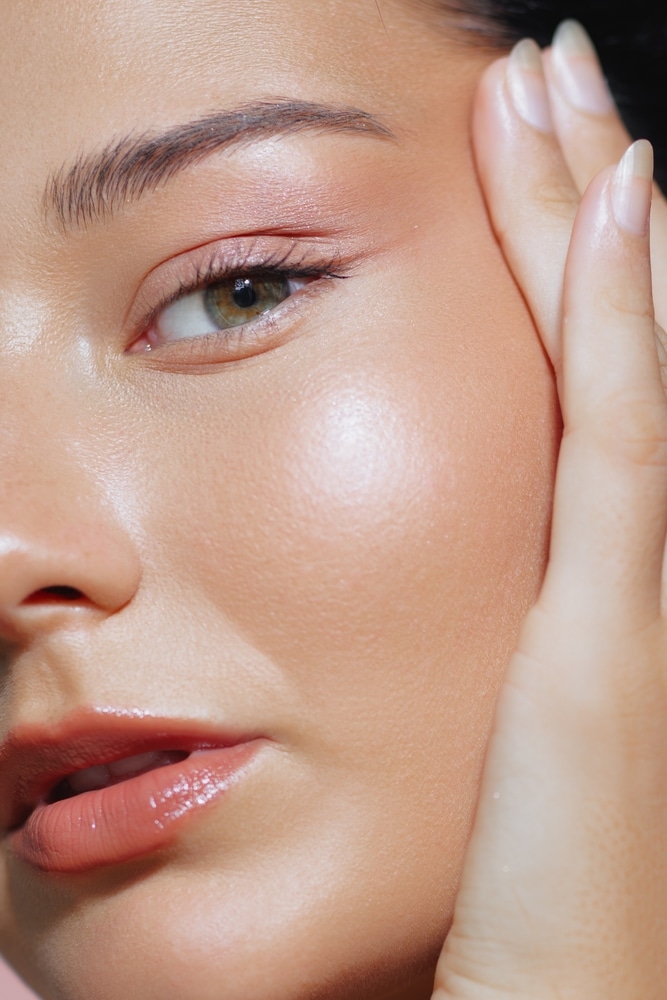 Close-up of a woman with glowing skin and natural makeup in a studio setting, ideal for highlighting spa facials, anti-aging treatments, and skincare routines.